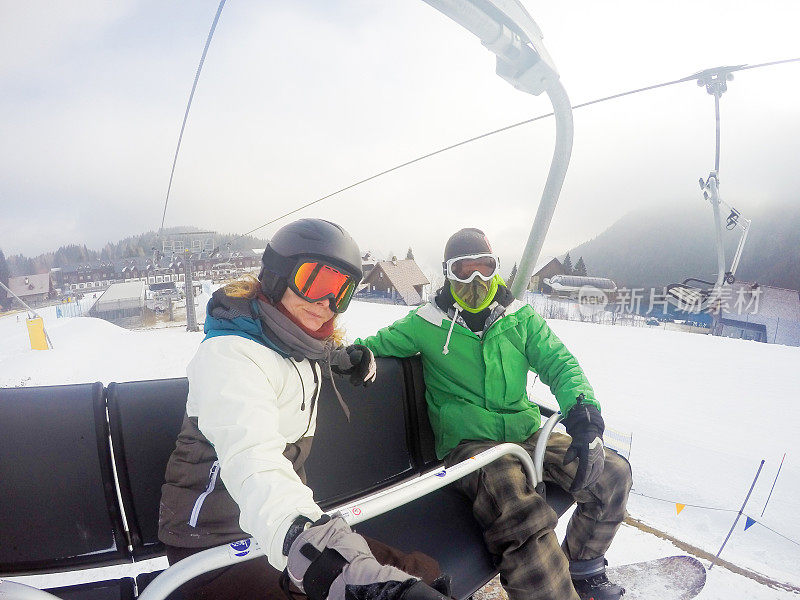 年轻女子和成年男子一起乘坐滑雪缆车