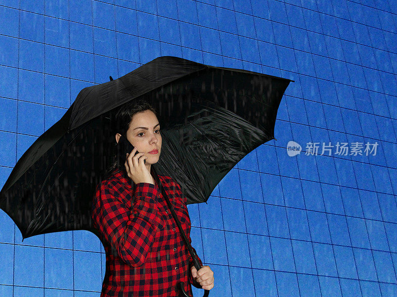 在以建筑为背景的城市景观中，拿着雨伞的女人