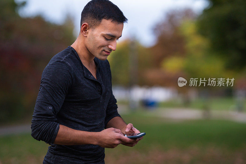 有魅力的印度男人用手机发短信