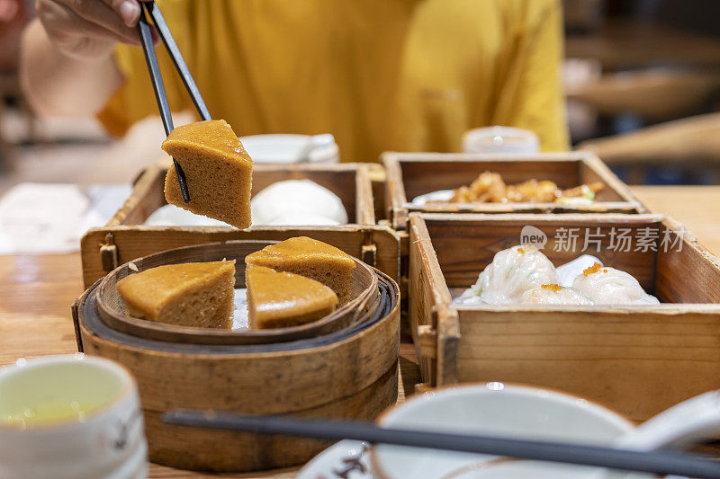 特写的一个亚洲人拿起一个广东dum叫红糖蛋糕在餐馆用筷子