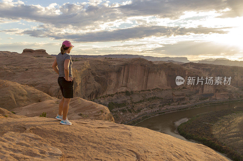 日落的女人站在砂岩山顶地狱报复区附近的摩押犹他州俯瞰科罗拉多河