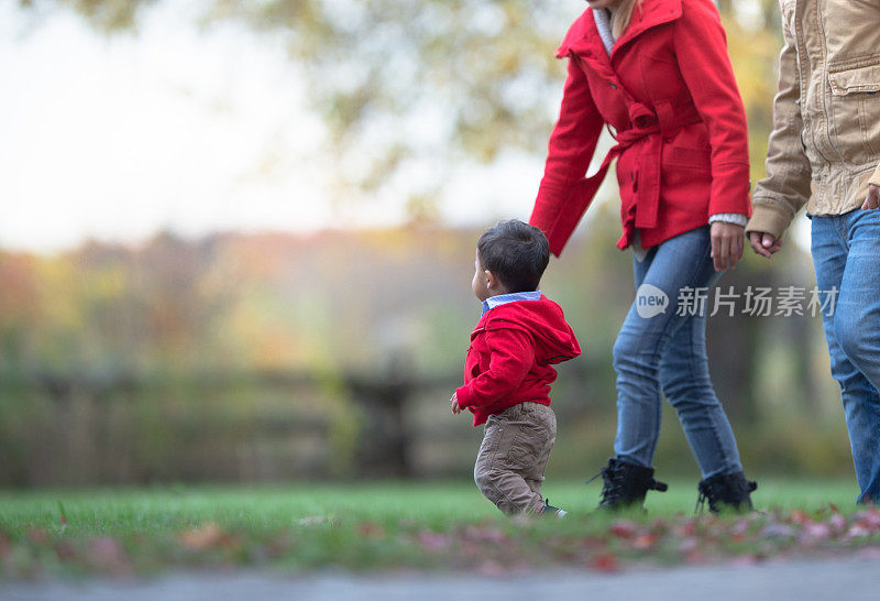 一家人在秋天和蹒跚学步的孩子一起散步