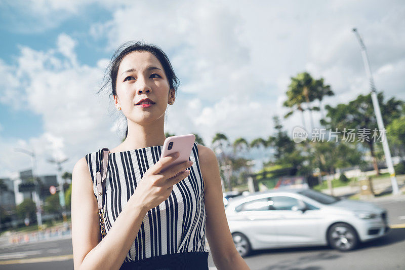 年轻女子用智能手机在城里通勤，