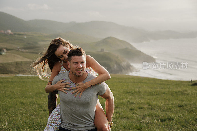 一对年轻夫妇在海边背着背包散步