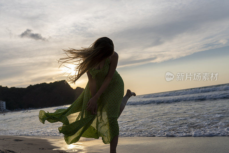 快乐的女人拿着帽子跑着跳着尽情享受海滩度假的生活。