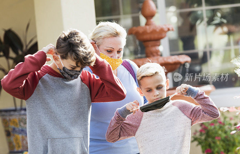 母亲和男孩们离开家时戴上了口罩