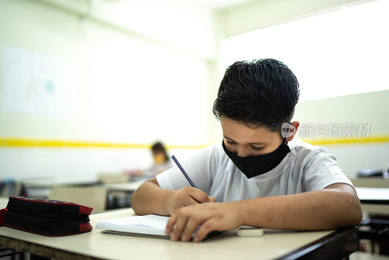 男生戴着口罩在教室里学习