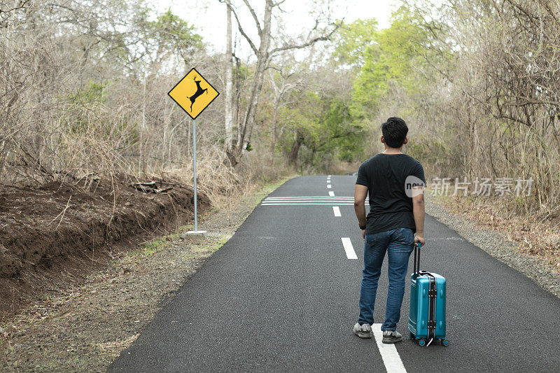 亚洲旅行家在森林里提着行李箱