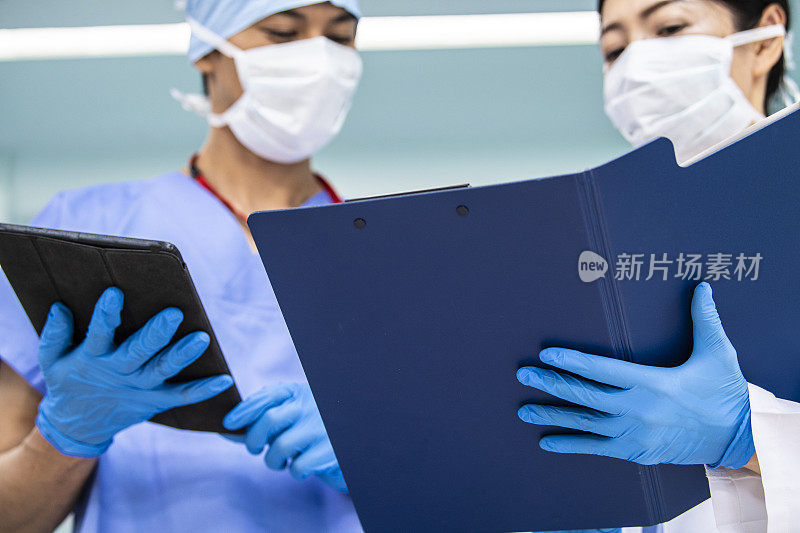 女医生和外科医生在医院的地板上检查病人的病历