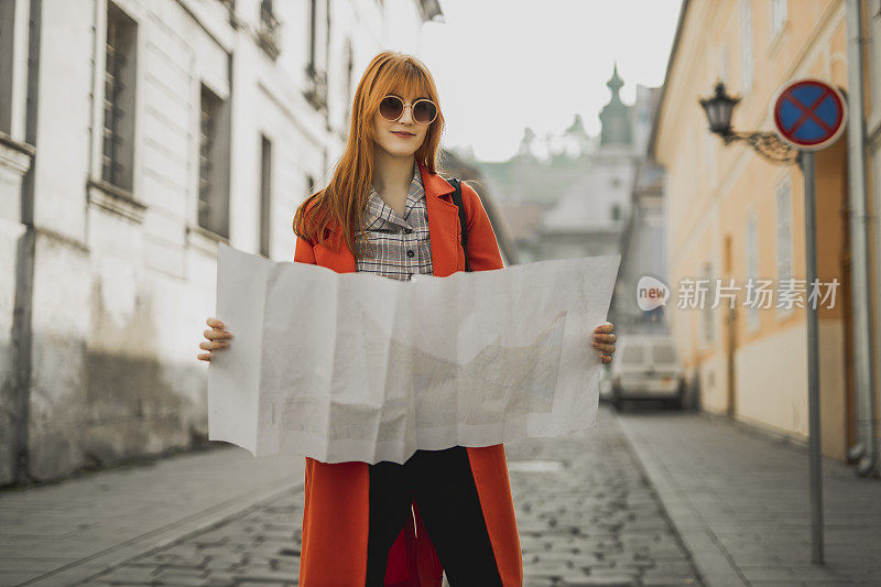 女旅行者在街上看城市地图。旅行，乐趣，度假的概念。