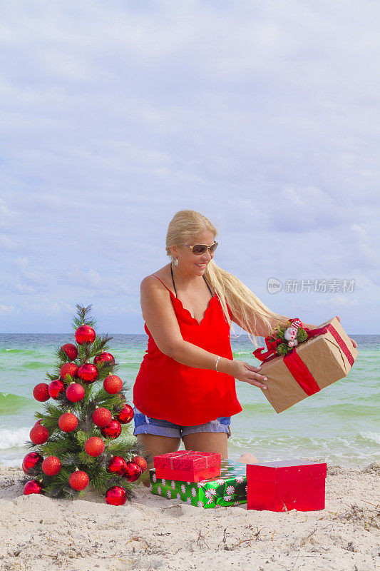 成熟的女人穿着一件红色的衬衫在迈阿密海滩，佛罗里达，美国，在她的假期里玩得开心，拿着她的圣诞礼物