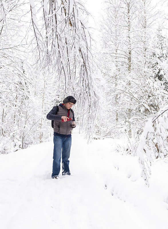 一个白人男人，在雪山里喝咖啡。冬季徒步旅行。那个人正在休息，享受着宁静。