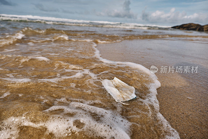 用过的一次性冠状病毒口罩被海浪冲到海滩上。