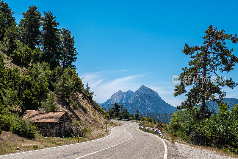 弯弯曲曲的道路景观和山川，路边有一所老房子