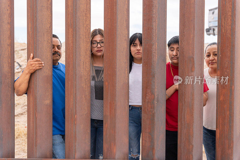 一群墨西哥人透过墨西哥奇瓦瓦州和美国德克萨斯州之间的国际边境墙往外看