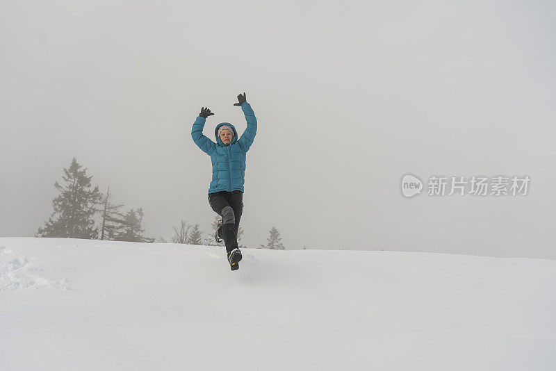 成熟的女人穿着皮大衣在雪地里奔跑