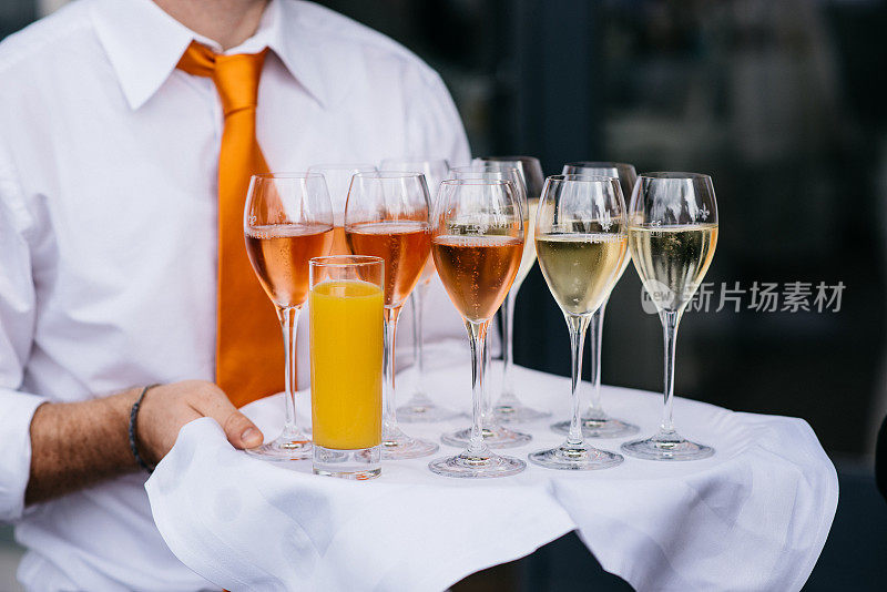 侍者端着一个盛有香槟和果汁的托盘。