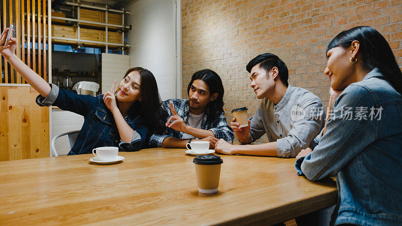 一组快乐的年轻亚洲人有一个伟大的时间和她的朋友自拍坐在一起在咖啡馆餐厅。