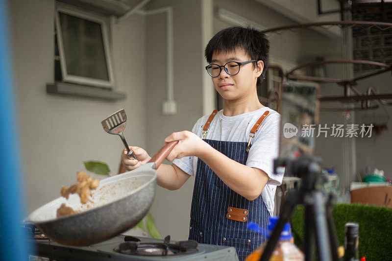 亚洲华人少年在后院厨房做视频，教烹饪广播。