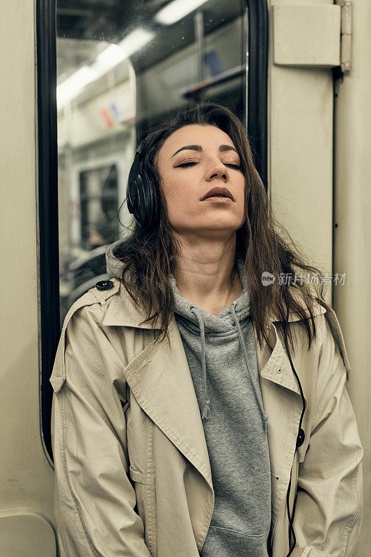 一个穿着米色风衣的女孩坐在地铁车厢里