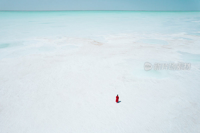 航拍的女人穿红色衣服走在盐湖上