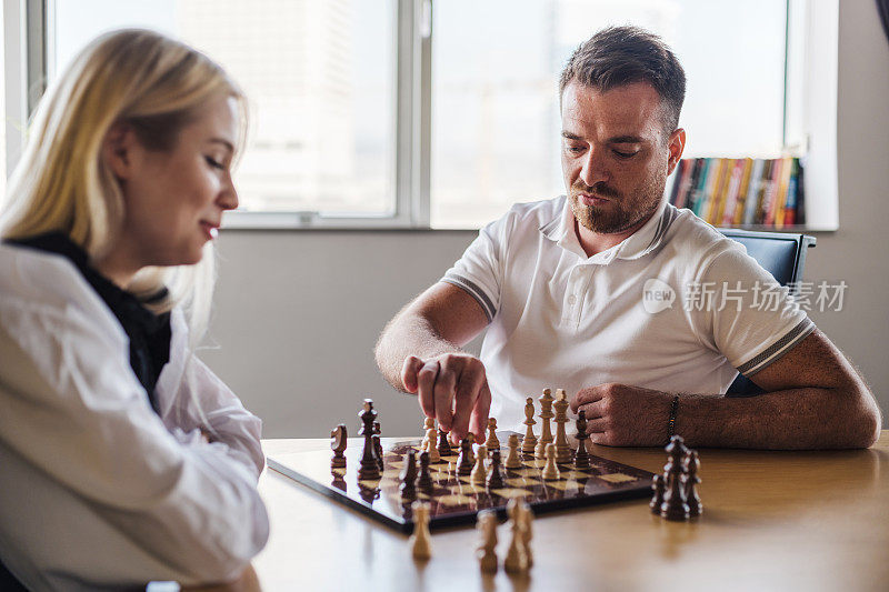 年轻的商人和女商人在办公室下棋，竞争和战略概念