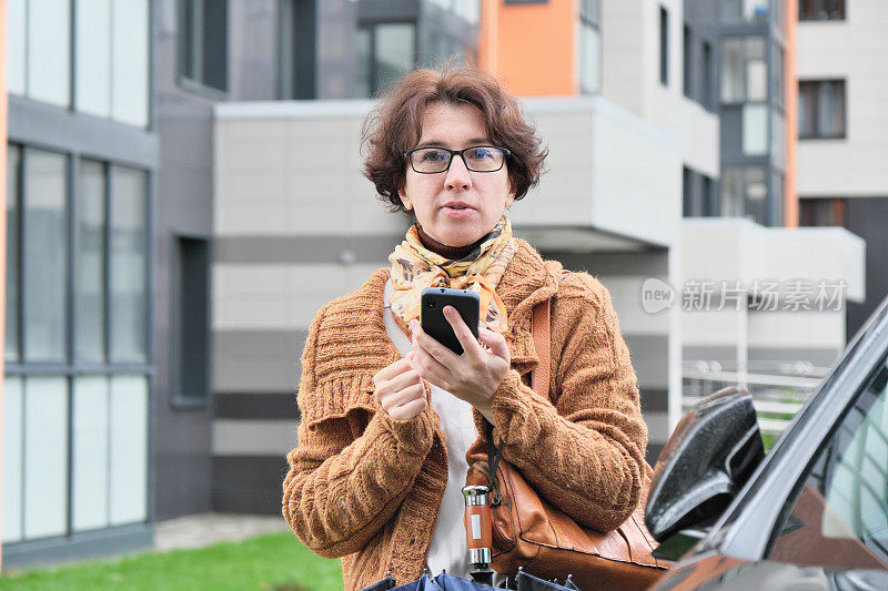 成熟的女人在城市的大街上等车