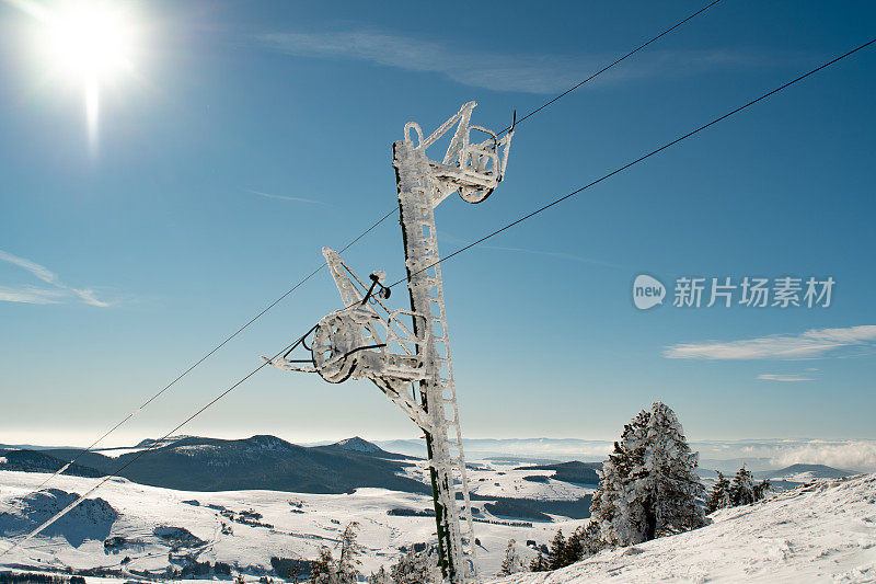 雪景前阳光下的滑雪缆车塔