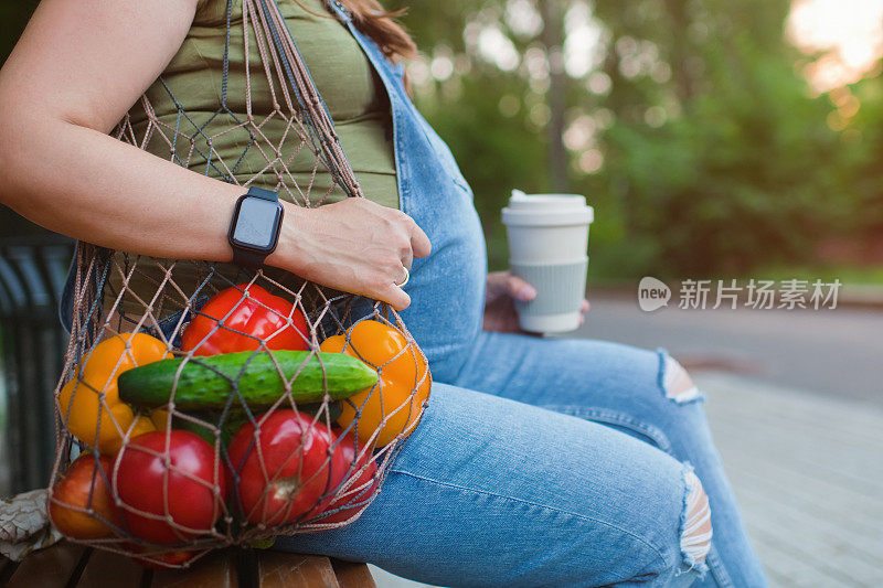 孕妇在夏天拿着环保袋在户外