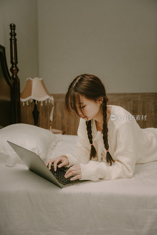 亚洲女孩躺在床上摆弄电脑