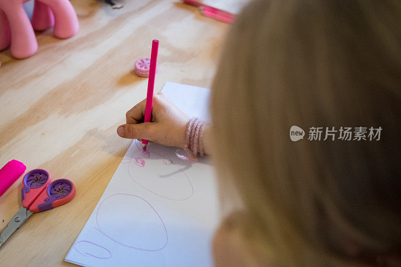 女孩用粉红色的铅笔在纸上画画
