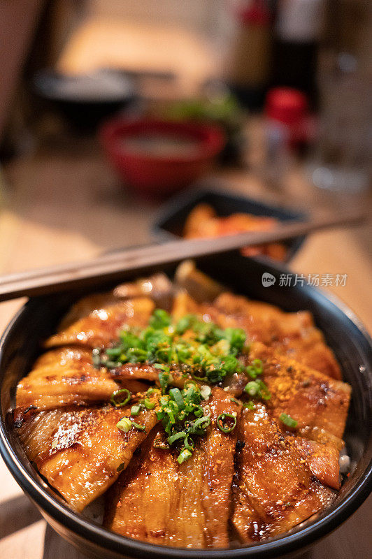 泰国一家日式餐厅的木桌上，烤猪肉米饭配上酱油装饰