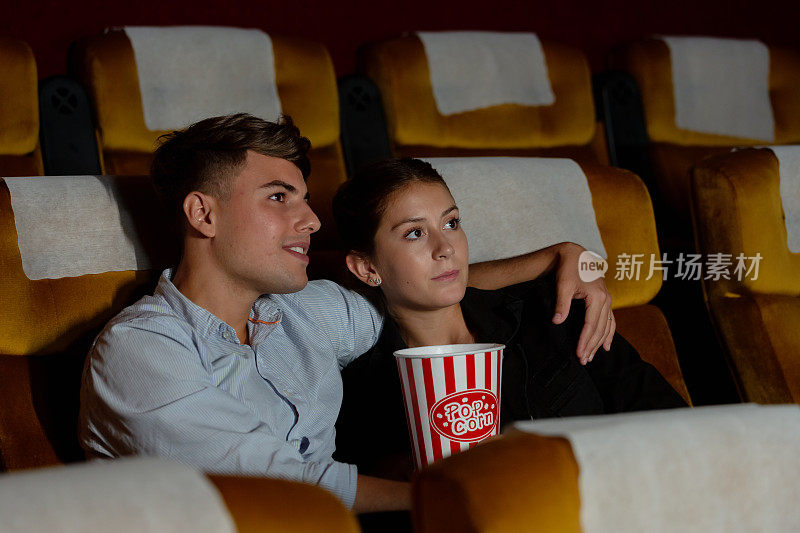 年轻夫妇在电影院看电影，很幸福