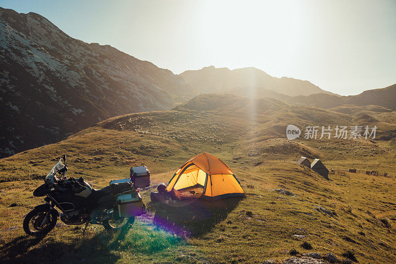 骑着摩托车和帐篷在山上的草坪上露营