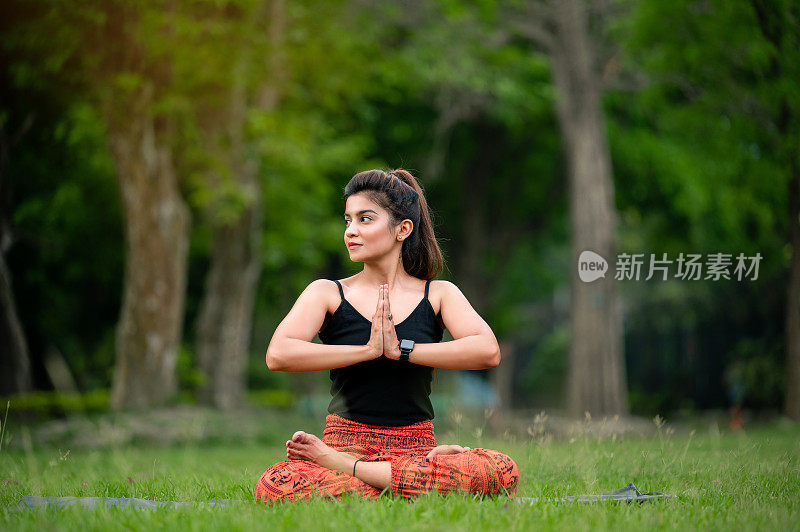 坐在莲花位的女人在户外做合十礼的姿势冥想