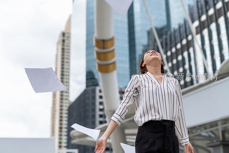 亚洲年轻漂亮的女商人在商业区把一堆文件纸扔向空中