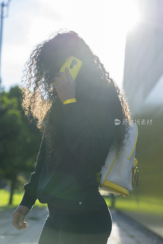 非洲裔拉丁妇女在街上用她的黄色手机打电话