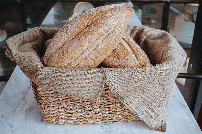 一组面包，面包放在柳条筐里放在桌子上，新鲜出炉的面包，芝麻和谷物面包
