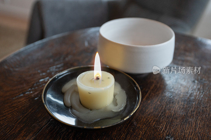 桌上放着蜡烛和白碗。点燃
