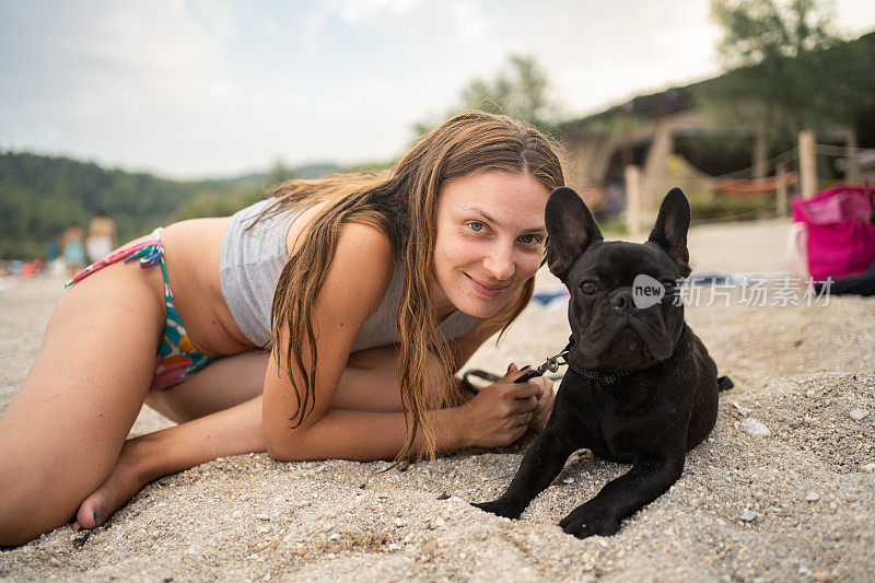 海滩上的女人和法国斗牛犬的肖像