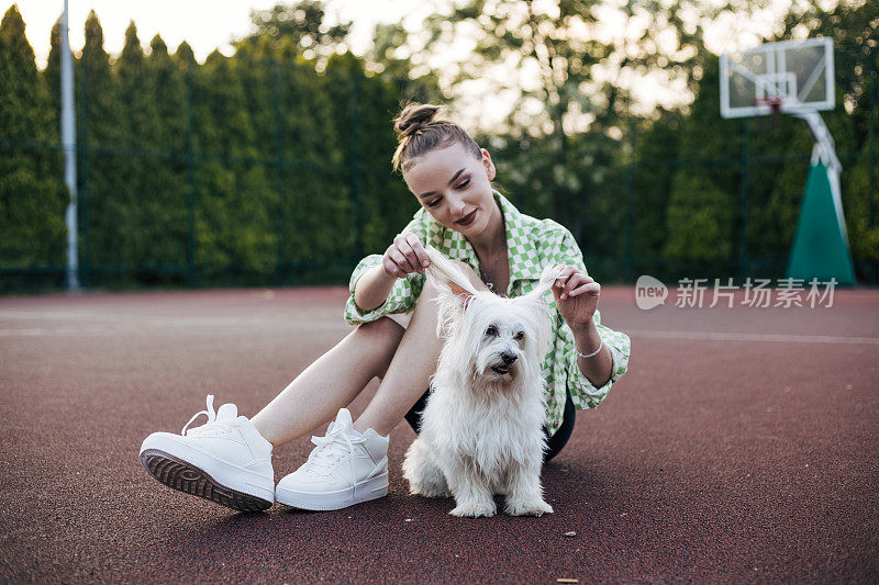 十几岁的女孩在篮球场上和狗狗玩耍