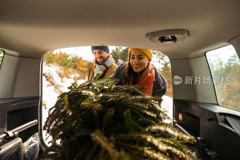 一对白人夫妇把圣诞树装进汽车后备箱