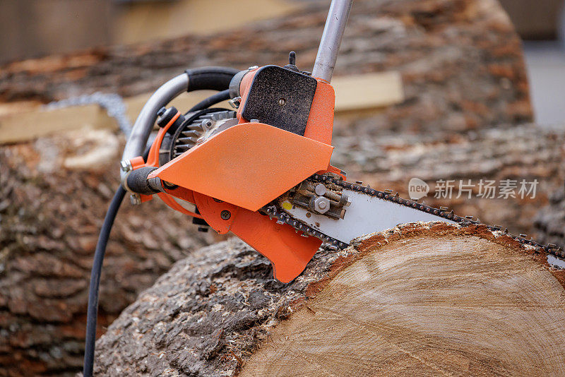伐木工在锯木厂用电动链锯锯树。用于砍伐树木、修剪树木、在野外扑灭火灾时切割防火带和收割木柴等活动的电锯。