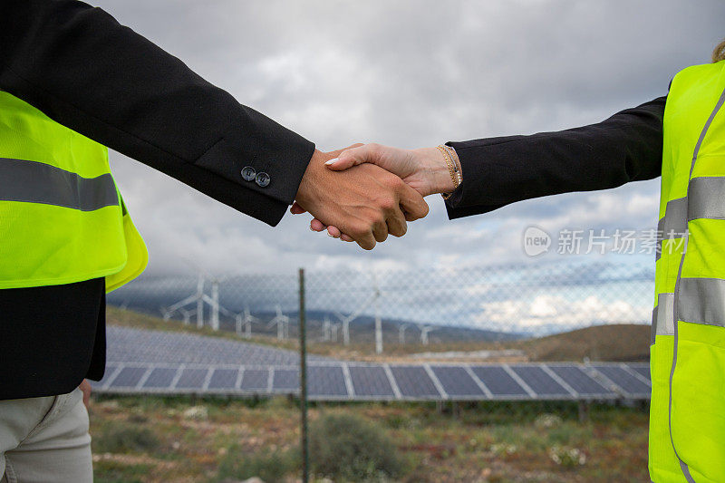 两个商人在太阳能农场握手，一男一女经理