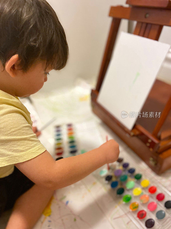 幼儿坐在画布上作画