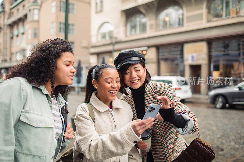 三个年轻女子在城市街道上使用电话