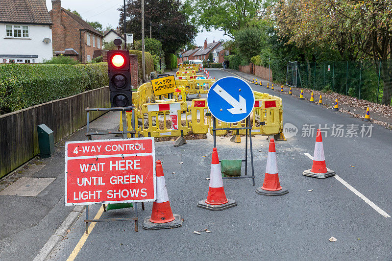 英国的道路工程正在挖掘当地的柏油路面，以修复地下的公用管道，并设置安全屏障和标志