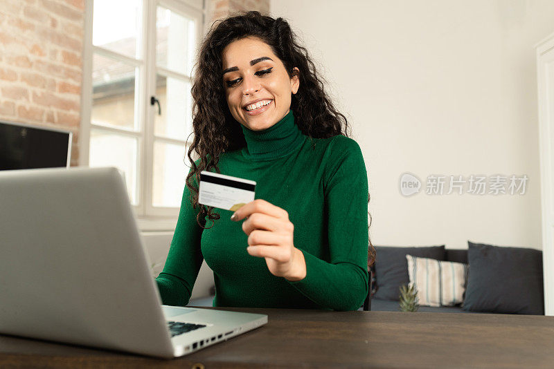 一个快乐的女人在家里放松，在网上购物