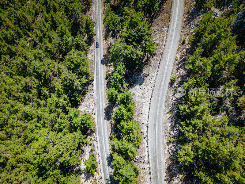 在森林山区的道路上行驶的车辆用无人机拍摄沥青弯道