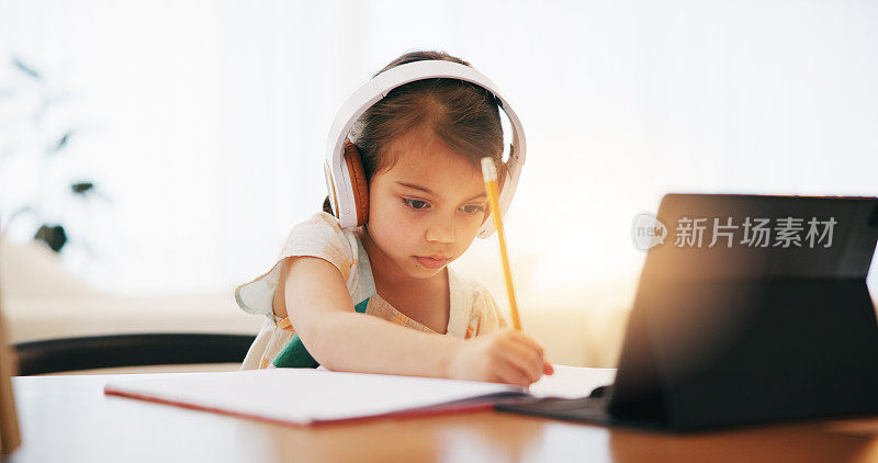 女孩，耳机和书写在书中用于在线学习，教育或学习在家里的桌子上。女性，儿童或小孩在家里用平板电脑，耳机或技术进行虚拟课堂笔记